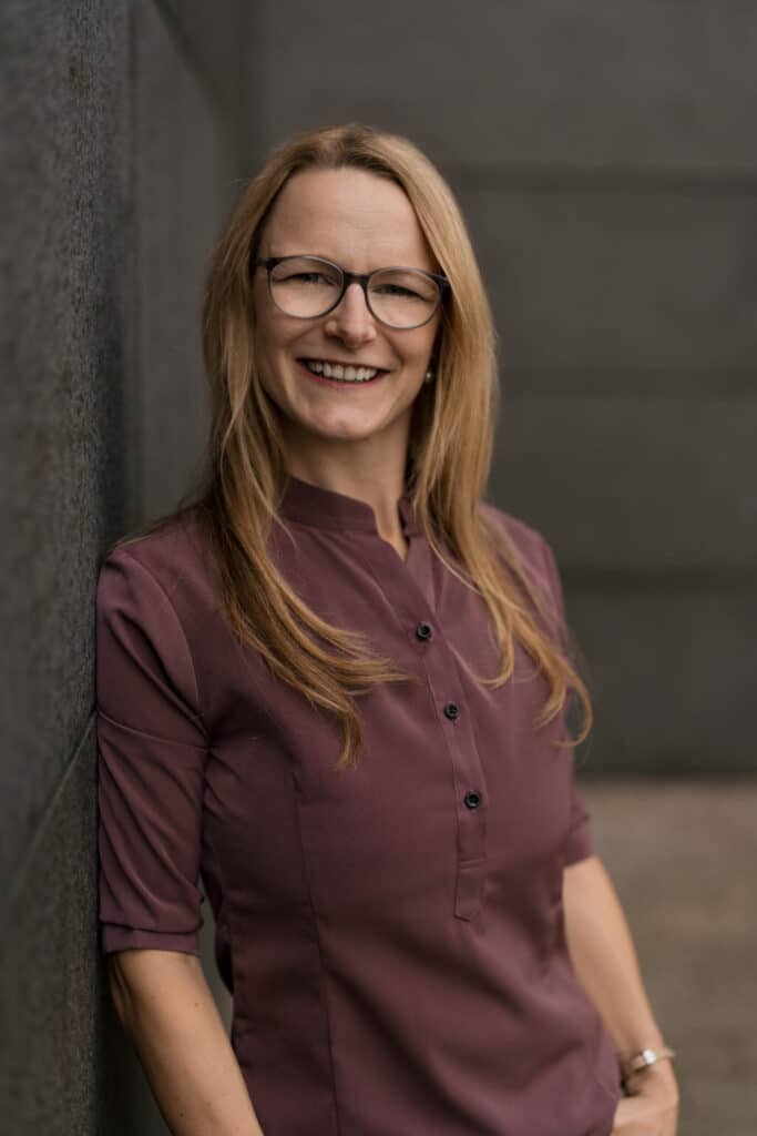 Portraibild einer Frau, die sich gegen eine Wand lehnt. - Bewerbungsfoto selber machen