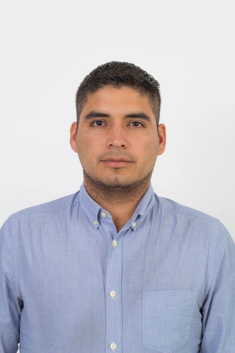 Portrait of a confident man in a blue shirt against a white background.